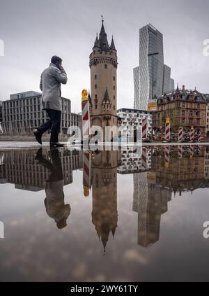 04. April 2024, Hessen, Frankfurt/Main: Um den mittelalterlichen Eschenheimer Turm (1400-1428, M) haben sich bei einer Dusche in der Frankfurter Innenstadt große Pfützen gebildet. Auf der rechten Seite spiegelt sich ein Hochhauskomplex, in dem sich auch das Marriott Hotel befindet, auf der Wasseroberfläche wider. Foto: Frank Rumpenhorst/dpa Stockfoto