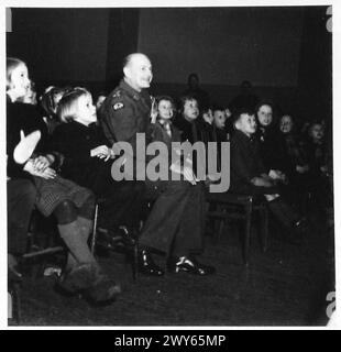 TRUPPEN-WOHLWOLLEN-PARTY FÜR NIEDERLÄNDISCHE KINDER - Brig H.P. Gardham, CBE, AQ, 12 Corps, schaut sich die Punch and Judy Show mit den Kindern an. Britische Armee, 21. Armeegruppe Stockfoto