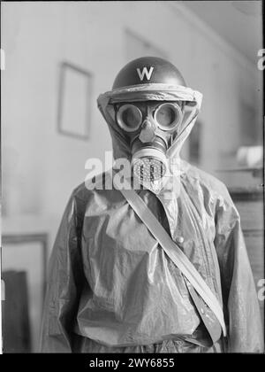 ANTI-GAS-KLEIDUNG FÜR LUFTSCHUTZWÄCHTER, 1941 - Ein halblanges Porträt eines Luftschutzwächters mit Gasschutzkleidung, Gasmaske und Stahlhelm. Das Gasschutz-Outfit ist ein Overall aus Ölleder, ähnlich wie Churchills „Sirenenanzug“. , Stockfoto