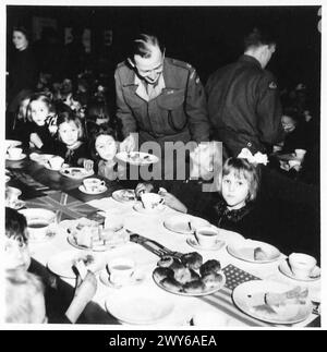 TRUPPEN-WOHLWOLLEN-PARTY FÜR NIEDERLÄNDISCHE KINDER - Maj A.R.H. Waring G II, Korps mit den Kindern während des Tees. Britische Armee, 21. Armeegruppe Stockfoto