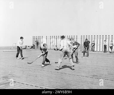 Über 50 britische Frauen und Kinder kehren im April 1944 auf der HMS Empress aus den Vereinigten Staaten zurück, wobei Jungen während der Atlantiküberquerung auf dem Flugdeck Hockey spielen. Stockfoto