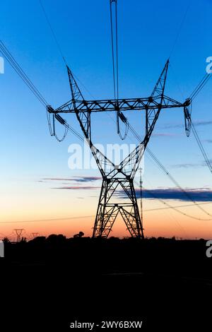 Hochspannungs-Übertragungstürme bei Sonnenuntergang Stockfoto