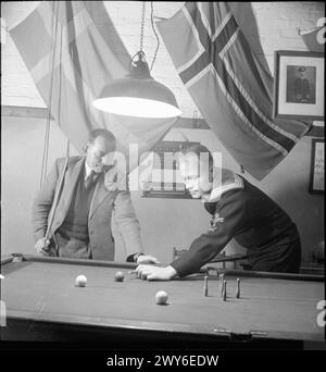 THE SEVEN SEAS CLUB: LIFE AT THE MERCHANT NAVY CLUB, EDINBURGH, SCHOTTLAND, 1943: Olaf Christensen (links) aus Dänemark und Olaf Lien, ein Seemann aus Norwegen, spielen im Seven Seas Club in Edinburgh eine Runde Billard. Darüber befinden sich die Flaggen zweier Länder, deren Bürger diesen Club befördern. , Stockfoto