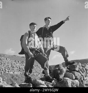 JUNGE WANDERER IN YORKSHIRE: DIE ARBEIT DER YOUTH HOSTEL ASSOCIATION IN WARTIME, MALHAM, YORKSHIRE, ENGLAND, VEREINIGTES KÖNIGREICH, 1944: zwei Jungs halten bei einem Spaziergang durch die Landschaft Yorkshires in der Sonne inne, um die Aussicht zu bewundern. einer von ihnen zeigt auf etwas in der Ferne. Sie haben ihren Spaziergang von einer Jugendherberge aus begonnen, wahrscheinlich in Malham. , Stockfoto