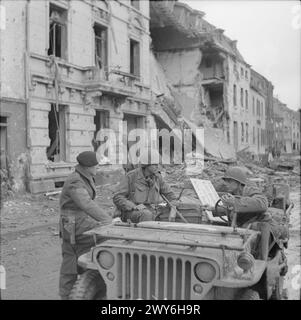 Britische Soldaten kommen durch Geilenkirchen und sprechen mit einem amerikanischen Soldaten im Jeep. Stockfoto