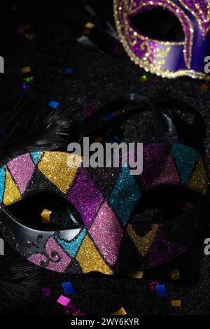 Nahaufnahme der Masquerade-Goldmaske mit Glitzern und Konfetten auf schwarzem Hintergrund. Stockfoto