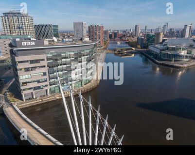 Drohnenfoto tief unten über dem Manchester Ship Canal mit der Media City Footbridge und den BBC Studios im Vordergrund mit MediaCityUK & Salford Quays Stockfoto