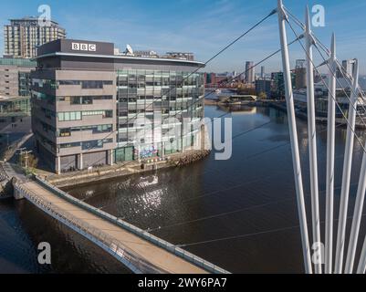 Drohnenfoto tief unten über dem Manchester Ship Canal mit der Media City Footbridge und den BBC Studios im Vordergrund mit MediaCityUK & Salford Quays Stockfoto