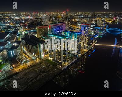 Nächtliche Drohnenfotografie von MediaCityUK und Salford Quays, UK mit Lightbox und Premier Inn im Vordergrund, Manchester in der Ferne Stockfoto