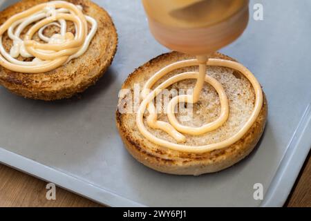 Schwabmünchen, Bayern, Deutschland - 17. März 2024: Mayonnaise Hamburgersoße auf einem gerösteten Hamburger Brötchen *** Mayonnaise Hamburgersoße auf einem gerösteten Hamburger Brötchen Stockfoto