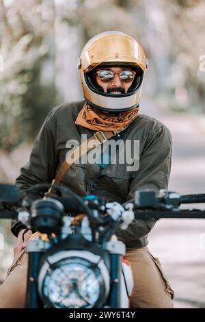 Motorradfahrer im Helm sitzt auf dem Fahrrad mit erhöhtem Rücksitz Stockfoto