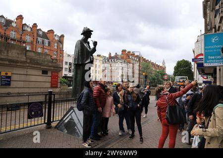 London, Großbritannien: Touristen posieren für ein Foto in der Nähe der berühmten Sherlock Holmes-Statue an der U-Bahn-Station Baker Street in London Stockfoto