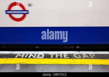 London, Großbritannien - 24. März 2024; denken Sie an die Gap-Warnung auf dem Bahnsteig mit verschwommener vorbeifahrender Londoner U-Bahn Stockfoto