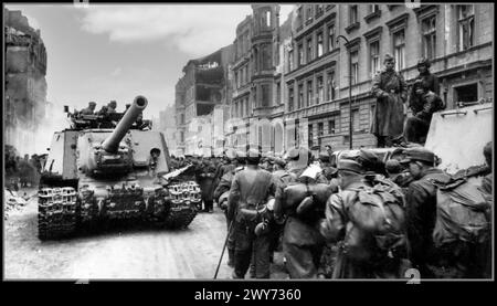 Berlin Nazi-Kapitulation 1945 WW2 Eine Kolonne deutscher Kriegsgefangener passiert durch sowjetische Selbstfahrlafetten ISU-122 entlang der Straße von Berlin Nazi-Deutschland Zweiten Weltkrieg die ISU-122 wurde als mächtiges Angriffsgewehr, selbstfahrende Haubitze und Langstreckenpanzerzerstörer eingesetzt. Stockfoto