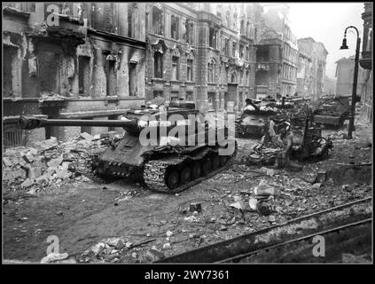PANZER WW2 Nazi-Berlin fällt in die russische Sowjetunion, die als Kolonne von sowjetischen schweren Panzern IS-2 auf einer schwer bombardierten und von Granaten beschädigten Straße in Zentral-Nazi-Berlin Deutschland 1945 der IS-2 ist ein sowjetischer schwerer Panzer, der zweite der IS-Panzerserie, benannt nach dem sowjetischen Führer Joseph Stalin. Der IS-2 war ein schwerer Panzer, der von der Sowjetunion während des Zweiten Weltkriegs eingesetzt wurde und für seine dicke Panzerung und 122-mm-Hauptgeschütze berühmt war, besonders gegen deutsche Tiger- und Pantherpanzer. Stockfoto