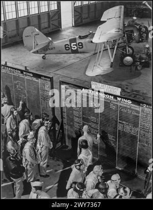 WW2 1942 USA Kadetten der amerikanischen Luftfahrtschule an der Marineflugstation Corpus Christi am Trainingsplan. Im Hintergrund des Fotos befindet sich ein Trainingsflugzeug der Naval Aircraft Factory N3N-3 (Seriennummer 2928, Hecknummer 659). Planen Sie Schulungstafeln mit der Warnung „DON’T GET GET GEFANGEN ÜBER DEN WOLKEN“ Corpus Christi USA Stockfoto