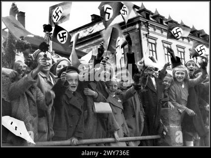 1938 Nazi-Propagandabild junger deutscher Kinder aus der tschechoslowakischen Stadt Trautenau (Trautenau ist der deutsche Name, Tschechoslowakisch ist Trutnov) grüßen die ankommenden Besatzungstruppen der Nazi-Wehrmacht. Trautenau Tschechoslowakei. Die militärische Besetzung der Tschechoslowakei durch Nazi-Deutschland begann 1938 mit der deutschen Annexion des Sudetenlandes, setzte sich mit der Schaffung des Protektorats Böhmen und Mähren fort und erstreckte sich bis Ende 1944 auf alle Teile der Tschechoslowakei Stockfoto