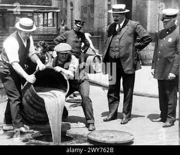 VERBOT IN DEN USA. New York City Deputy Police Commissioner John Leach beobachtet seine Agenten, wie sie Alkohol in einen Abfluss gießen, nach einer Razzia um 1925 Stockfoto