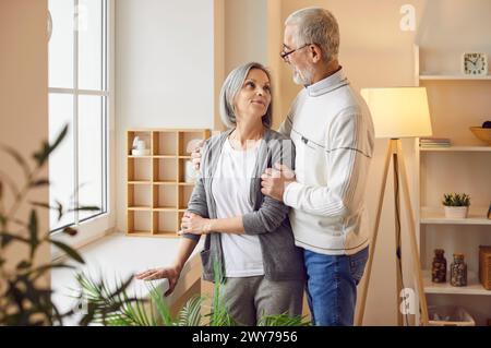Porträt eines älteren Ehepaares, das sich umarmt und lächelt und zu Hause zusammen steht. Stockfoto
