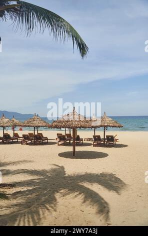 Strohschirme und Sonnenliegen am leeren Kiesstrand mit Meer im Hintergrund Stockfoto