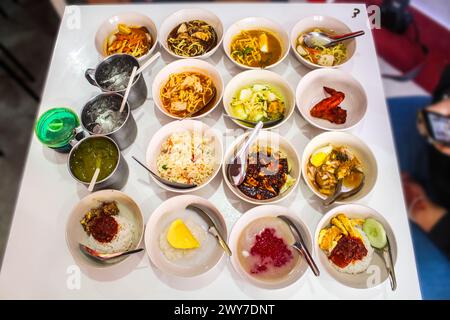 Teller mit mehreren essbaren Speisen, traditionelles malaysisches Essen, unter den Gerichten sind Nasi Lemak, Me Kari, Cendol, tandori Huhn, Pulut mangga, nasi Stockfoto