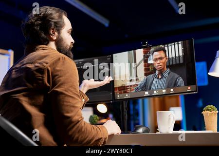 Entwickler, der Software-Debugging durchführt, unterstützt von afroamerikanischen Kollegen bei Videoaufnahmen und überprüft Fehler in Codezeilen. Mann, der Programmierfehler korrigiert, unterstützt von Kollegen bei Internet-Videokonferenzen Stockfoto