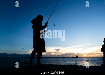 Salvador, Bahia, Brasilien - 13. April 2019: Fischer werden bei Sonnenuntergang in Ponta do Humaita in der Stadt Salvador, Bahia, in Silhouette gesehen. Stockfoto