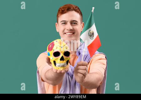 Junger Mann mit mexikanischer Flagge und bemaltem Schädel auf grünem Hintergrund Stockfoto