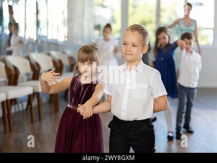 Kinder, die während des Tanzkurses zu zweit Ballsaal-Tänze üben Stockfoto