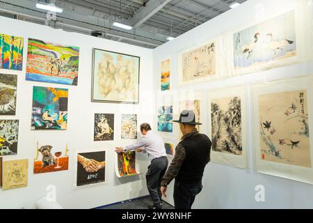 New York, NY, USA. April 2024. ARTEXPO New York wurde am Pier 39 auf der Lower East Side eröffnet, wo Galerien und Künstler zeitgenössische Kunst einem engagierten Publikum zeigen. Ein Galerist hängt Kunst in der Galerie American Asian Arts/Shanghai Calligraphy Institute. Quelle: Ed Lefkowicz/Alamy Live News Stockfoto