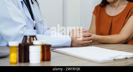 Arzt geben Hoffnung. Junge Ärztin hält die Hand einer älteren Patientin, um sie während der medizinischen Beratung zu trösten Stockfoto