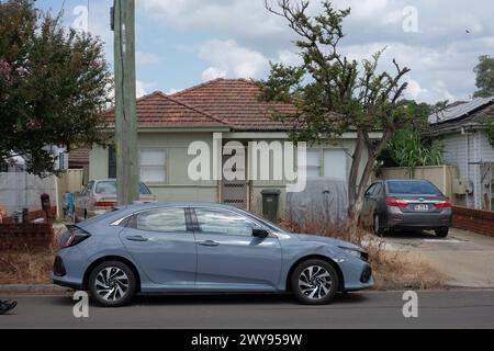 Fibro House mit zwei Autos in der Einfahrt, eines im Vorgarten und eines auf der Straße im Vorort Canley Vale Stockfoto