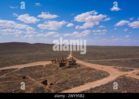 Aus der Vogelperspektive eines verlassenen Hotelgebäudes in einer riesigen Wüstenlandschaft mit klarem blauem Himmel Stockfoto