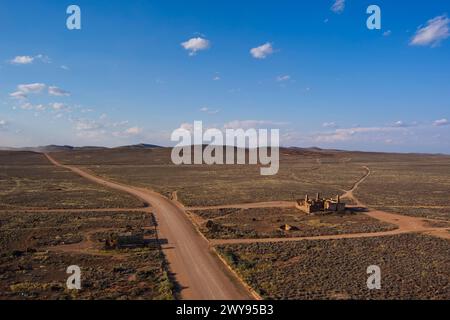 Aus der Vogelperspektive eines verlassenen Hotelgebäudes in einer riesigen Wüstenlandschaft mit klarem blauem Himmel Stockfoto