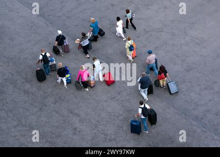 Gruppe von Personen, die mit ihren Koffern auf Rädern entlang asphaltierten Flächen laufen, Blick von oben Stockfoto