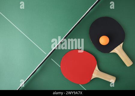 Set aus Tischtennispong-Paddles und orangenem Ball auf grünem Spieltisch. Draufsicht. Stockfoto