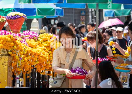 Eine ältere asiatische Frau trägt einen Opferkorb im Erawan-Schrein in der Innenstadt von Bangkok. Thailand. Stockfoto