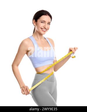 Glückliche junge Frau mit Maßband, das ihren schlanken Körper vor weißem Hintergrund zeigt Stockfoto