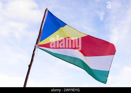 Flagge der Seychellen winkt im Wind unter bewölktem blauen Himmel an einem sonnigen Tag, Nahaufnahme Foto Stockfoto
