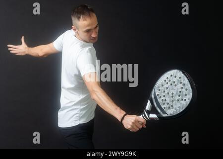 Porträt eines Mannes, der Paddeltennis spielt, in Position, um einen schwarzen, isolierten Hintergrund zu treffen. Vorderansicht. Stockfoto