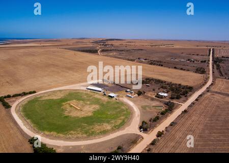 Aus der Vogelperspektive auf eine ländliche Landschaft mit kreisförmigem Grünfeld, Bauernhäusern und Straßen inmitten von trockenem Ackerland Stockfoto