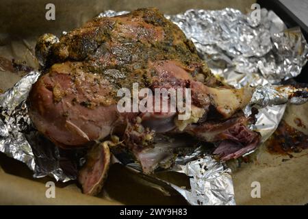 Essen, Kochen köstliches Fleisch, Schafskeule auf dem Knochen mariniert und im Ofen gebacken. Ein großes Stück Lammfleisch auf braunem Pergamentpapier. Stockfoto