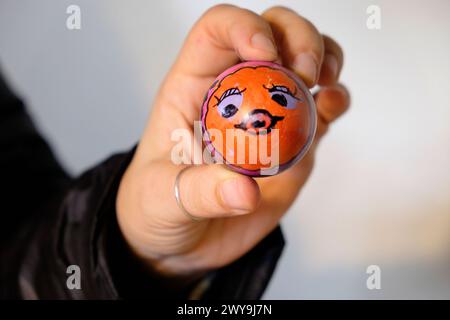 Hand mit einem bemalten hart gekochten Ei mit dem Gesicht eines Fisches für den Einsatz bei einem Ostereierrollwettbewerb im März 2024 Wales UK KATHY DEWITT Stockfoto