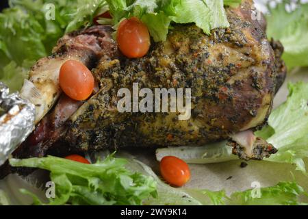 Essen, Kochen köstliches Fleisch, Schafskeule auf dem Knochen mariniert und im Ofen gebacken. Ein großes Stück Lammfleisch auf braunem Pergamentpapier. Stockfoto