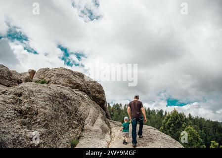 Großer Blick auf Papa und Sohn, die im Sommer auf Felsen wandern. Stockfoto