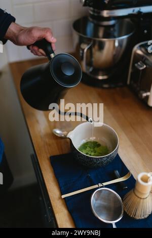 Wasserkocher gießen Sie kochendes Wasser in Matcha-Teepulver Stockfoto