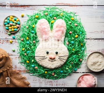 Blick von oben auf den Osterhasenkuchen und die Dekoration auf dem weißen Holztisch. Stockfoto