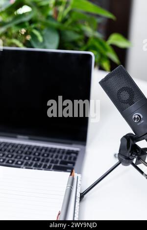 Podcasting-Mikrofon mit Laptop und Notizblock Stockfoto