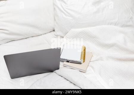 Arbeiten Sie mit Laptop auf einem gemütlichen Bett Stockfoto