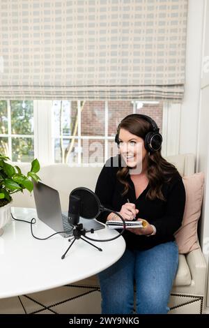 Eine lächelnde Frau, die einen Podcast von zu Hause aus moderiert Stockfoto